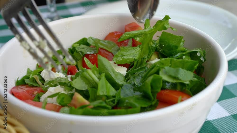 Greek salad with cheese and herbs is mixed with a fork and spoon . High quality 4k footage Greek salad with cheese and herbs is mixed with a fork and spoon . High quality 4k footage
