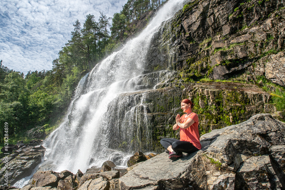  Frau macht Yoga im Freien vor einem Wasserfall