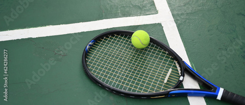 A racket and ball on tennis court with copy space. Outdoor sports and healthy lifestyle concept © Prathankarnpap