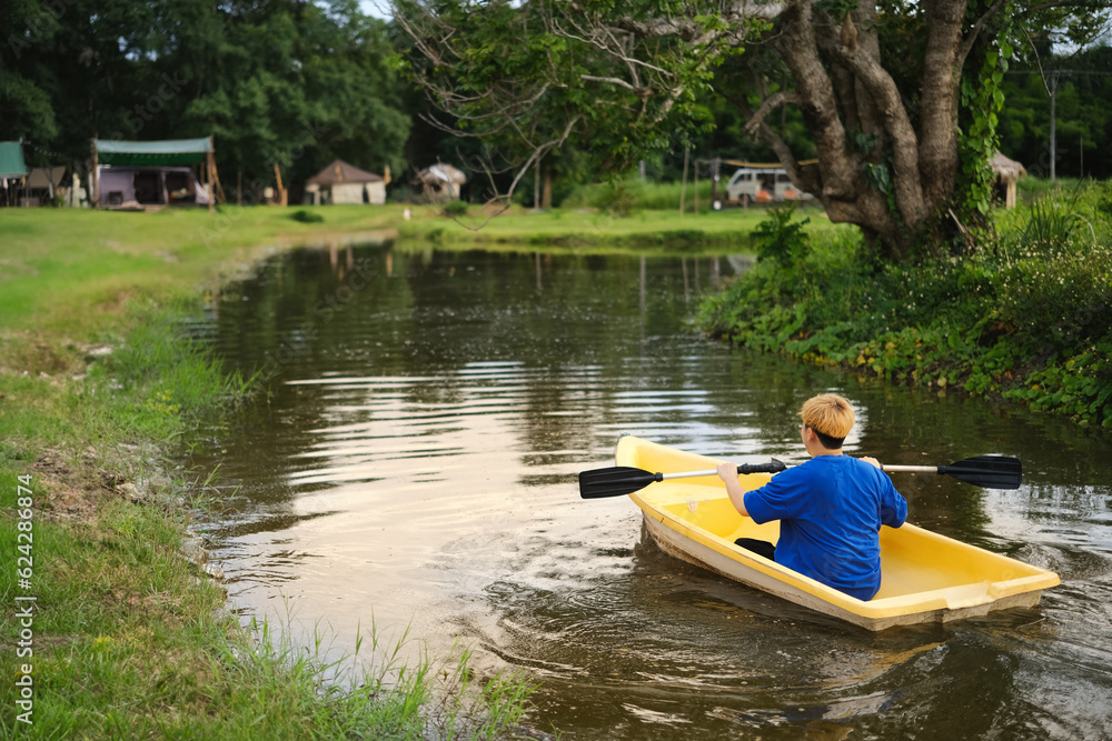 Rear view of man rowing a boat over a lake surrounded by trees. Tavel, tourism recreation outside concept Rear view of man rowing a boat over a lake surrounded by trees. Tavel, tourism recreation outside concept