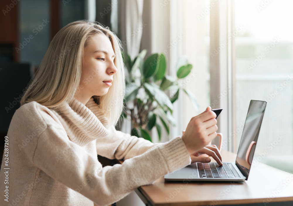 Young woman holding credit card and using laptop computer. Young woman holding credit card and using laptop computer.