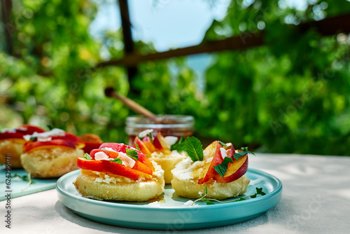 Mini sandwiches with cream cheese, nectarines, coconut, mint and honey. Delicious summer peaches toast, healthy lunch idea.