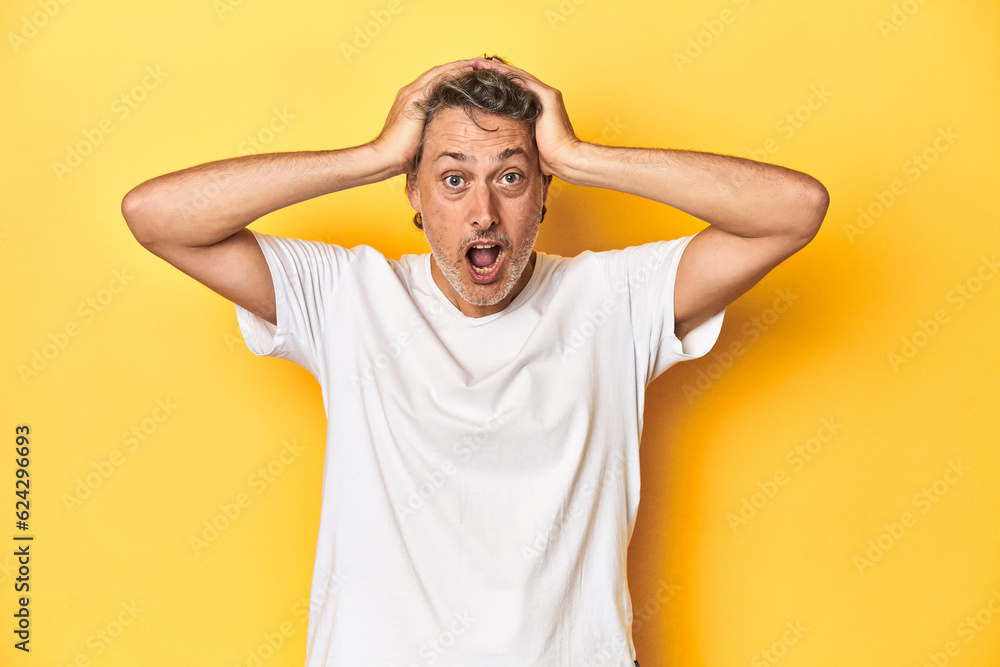 Middle-aged man posing on a yellow backdrop screaming, very excited, passionate, satisfied with something. Middle-aged man posing on a yellow backdrop screaming, very excited, passionate, satisfied with something.