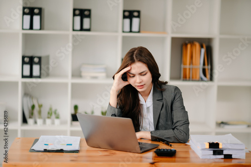 Woman who is tired and overthinking from working with tablet and laptop at modern office..