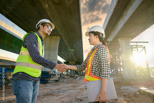 An engineer supervising the construction of new roads and inspecting the construction site shakes hands with a civil engineer