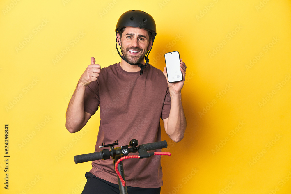 Man on electric scooter checking mobile app on yellow studio background. Man on electric scooter checking mobile app on yellow studio background.