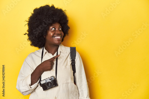 Stylish African-American woman with vintage camera Stylish African-American woman with vintage camera.smiling and pointing aside, showing something at blank space.