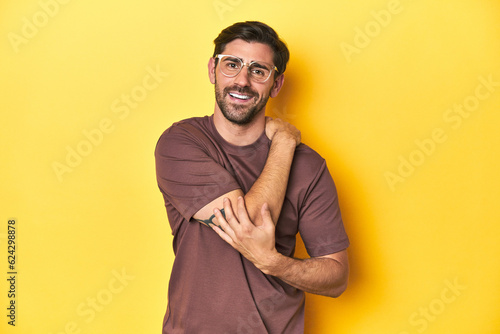 Man stretching arm on a yellow studio background. photo