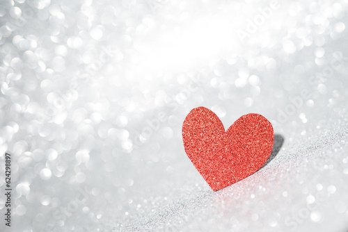 Red heart on a silver background with beautiful bokeh. Valentine's Day is the feast of lovers