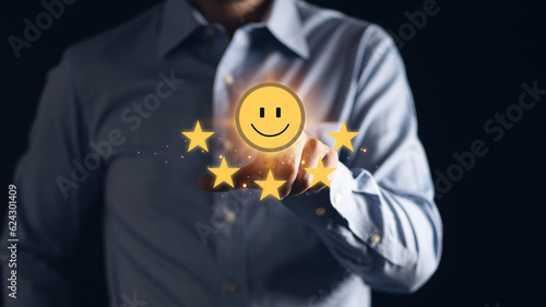 Businessman using a mobile phone to point to a smile face and five stars icon, representing positive reviews and customer satisfaction. Building credibility and trust with happy customers