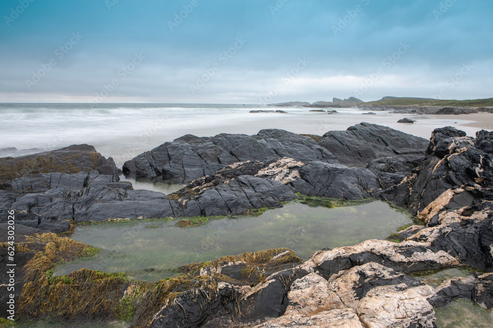 A rocky pool of water on a beach in the Isle of Islay.