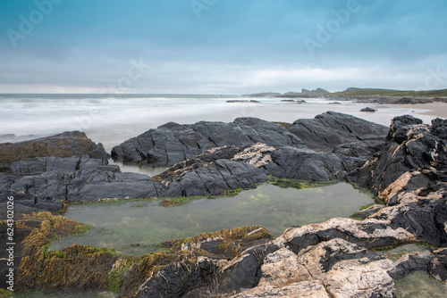 Fotografie A rocky pool of water on a beach in the Isle of Islay.