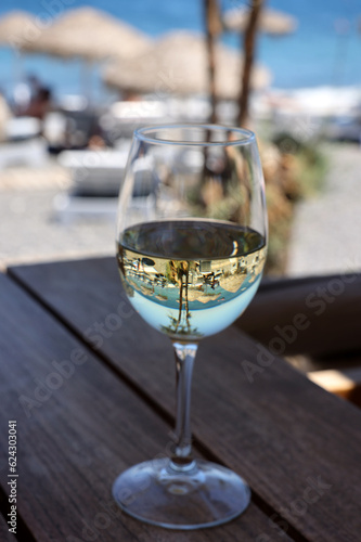 A glass of white wine at a restaurant by the beach in Kamari, Santorini. Greece