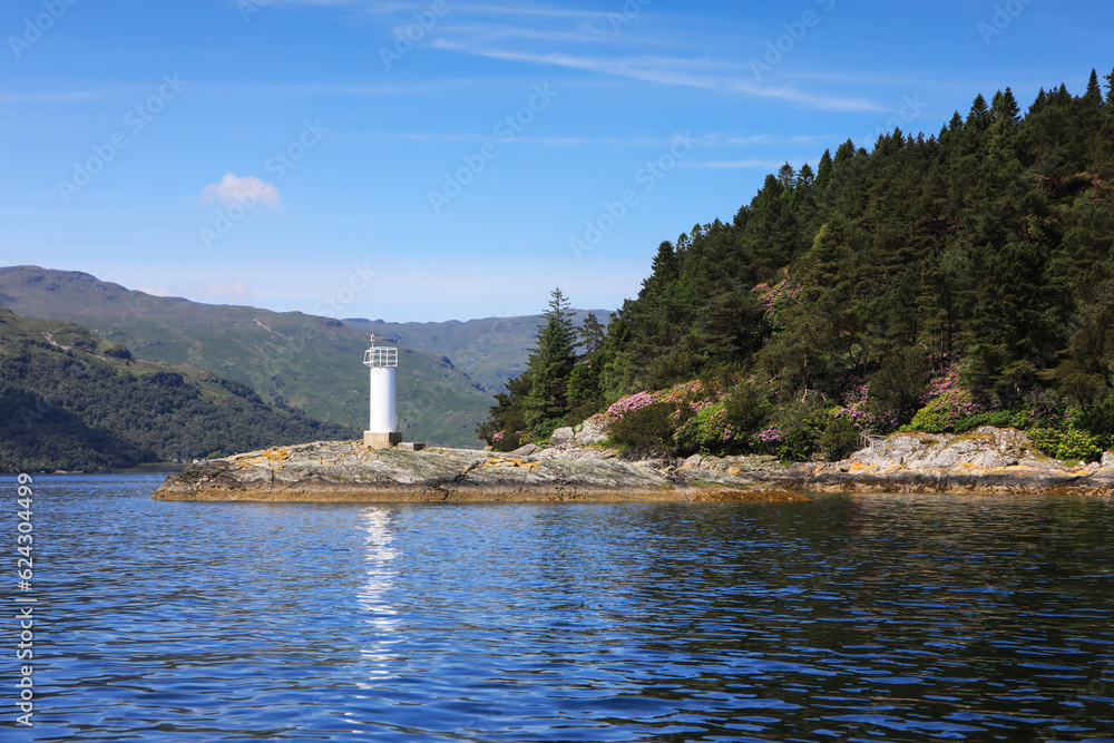 A white lighthouse stands on the banks of Loch Goil, Scotland.