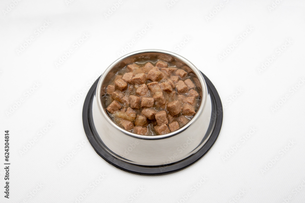 Wet cubical pieces pile isolated on white background. Bowl of meat dog food. Round metal bowl for pets with food. Wet cubical pieces pile isolated on white background. Bowl of meat dog food. Round metal bowl for pets with food.