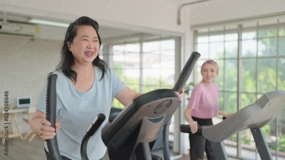 Happy elderly women and daughter enjoy exercising on the machine in living room at home on weekend. Elderly lifestyle, Famity activity Happy elderly women and daughter enjoy exercising on the machine in living room at home on weekend. Elderly lifestyle, Famity activity