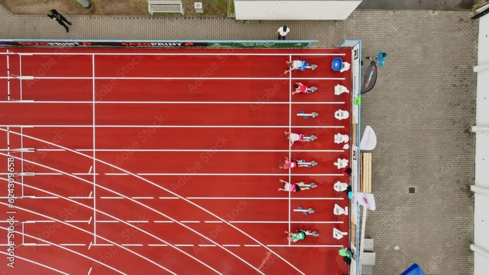 Obstacle course with running athletes on a tartan track. Drone move to the left Obstacle course with running athletes on a tartan track. Drone move to the left