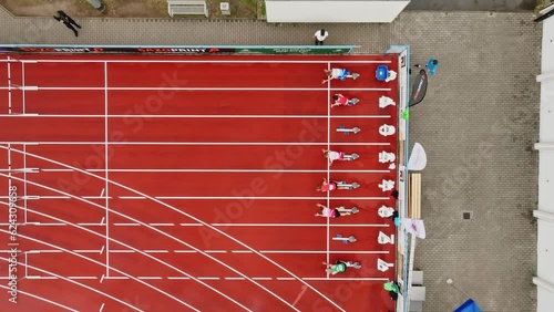 Obstacle course with running athletes on a tartan track. Drone move to the left