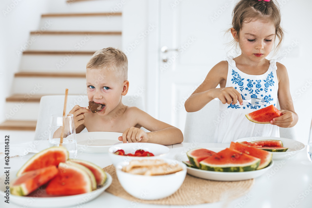 Two cute kids preschooler eating fresh juicy watermelon and ice-cream