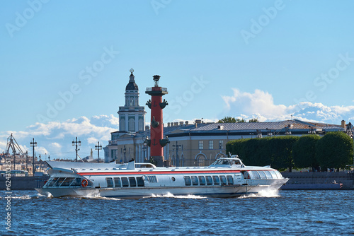 Passenger hydrofoil sails through the sightseeing places of the European city on a clear summer day. Tourists on a boat trip on a white high-speed ship float along the canals and rivers .