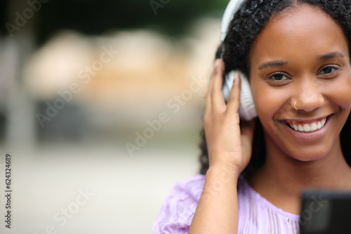 Black woman looks at you listening music