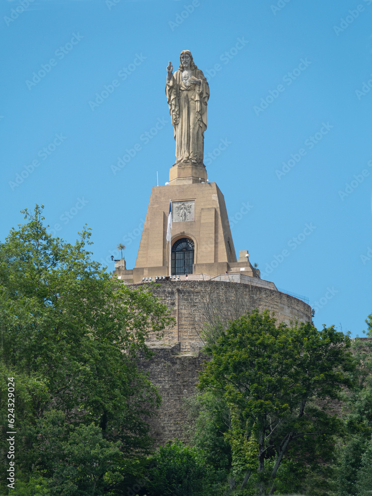 Obraz premium Jesus statue over San Sebastian. Dominating the top of the Urgull hill is this Sacred Heart Christ statue overlooking San Sebastian. Blue sky background.