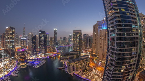 Aerial view to Dubai marina skyscrapers around canal with floating boats day to night timelapse © neiezhmakov