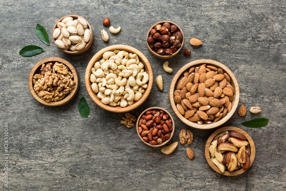 mixed nuts in wooden bowl. Mix of various nuts on colored background. pistachios, cashews, walnuts, hazelnuts, peanuts and brazil nuts