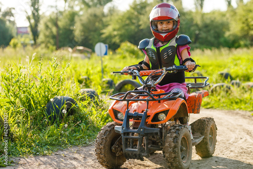 The little girl in protective clothing. Electric quad bike electric car for children popularizes green technology.