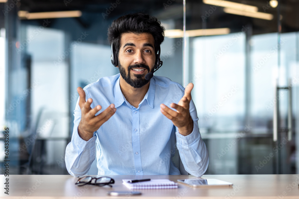 © Tetiana - Webcam view, video call online meeting businessman smiling and talking friendly with colleagues clients, successful hispanic worker looking at camera working inside office with headset phone. © Tetiana - Webcam view, video call online meeting businessman smiling and talking friendly with colleagues clients, successful hispanic worker looking at camera working inside office with headset phone.