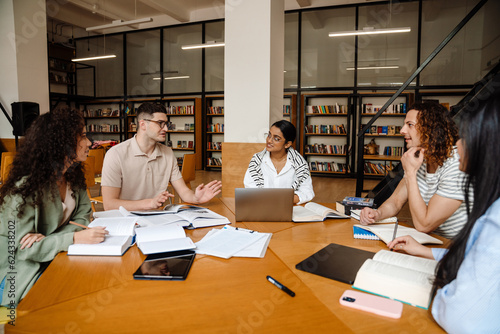 Group of students having discussion while studying together in library