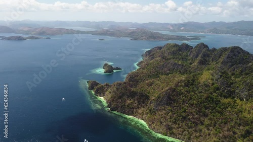 Tropical island surrounded by beach and boats at Palawan Philippines - High angle aerial with coastal background photo