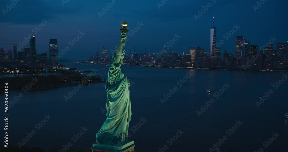 Aerial Helicopter Cinematic View of the Statue of Liberty with Manhattan Skyline Cityscape in the Evening. Panoramic View of New York City Skyscrapers and Jersey City Buildings at Sunset