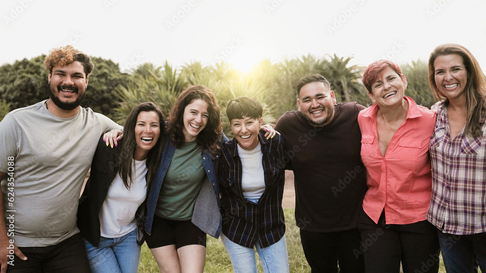 Multi-generational group of people smiling at camera outside park city during summer day - Multiracial friends celebrate holiday vacations outdoors Multi-generational group of people smiling at camera outside park city during summer day - Multiracial friends celebrate holiday vacations outdoors