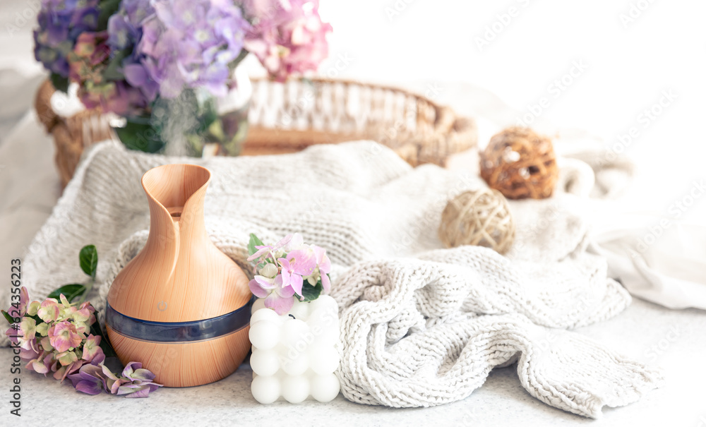 Aroma oil diffuser lamp, flowers and knitted element on a blurred background. Aroma oil diffuser lamp, flowers and knitted element on a blurred background.