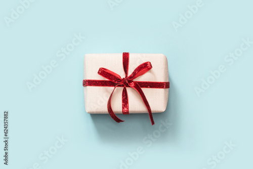 Christmas gift with red ribbon on blue background. View from above. photo