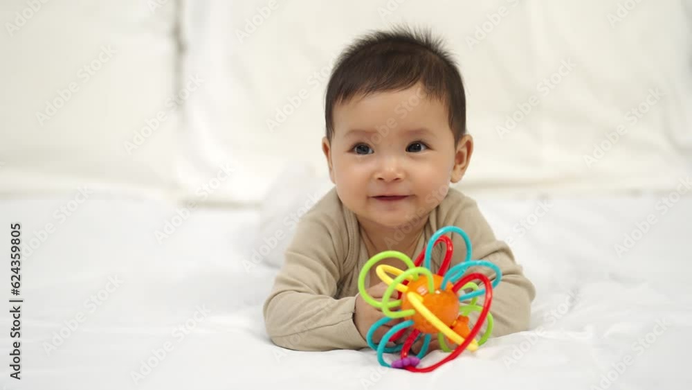 infant baby playing with colorful rubber bites toy on a bed infant baby playing with colorful rubber bites toy on a bed