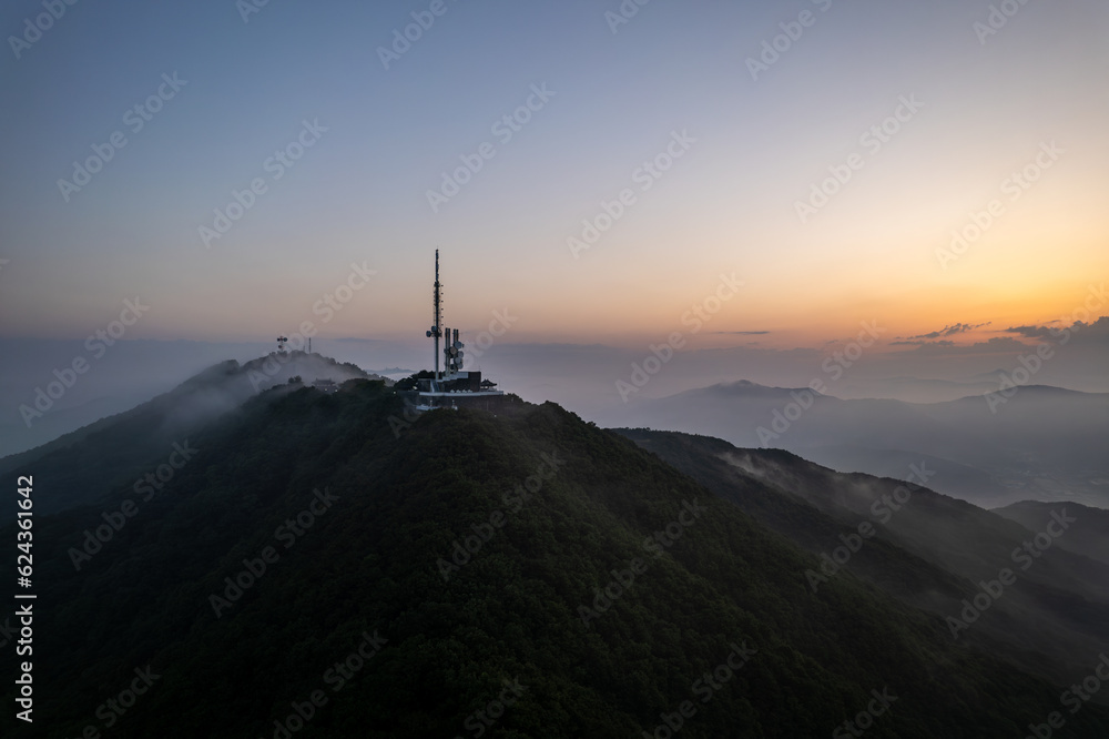 Aerial view of mountain peak against sky surrounded by fog during sunrise