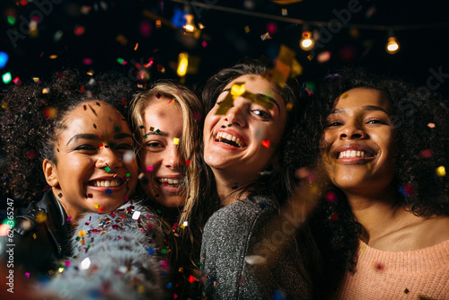 Four happy females taking selfie under colorful confetti