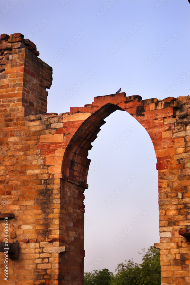 Carved Stone view of ruined walls and arches with Qutub Minar in background at Qutub Complex known as Unesco World Heritage Site, New Delhi, India, Asia. Carved Stone view of ruined walls and arches with Qutub Minar in background at Qutub Complex known as Unesco World Heritage Site, New Delhi, India, Asia.