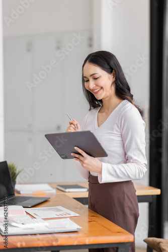 Young indian woman or asian woman using tablet relaxing on workplace officce. Latin business woman work in office, copy space. 