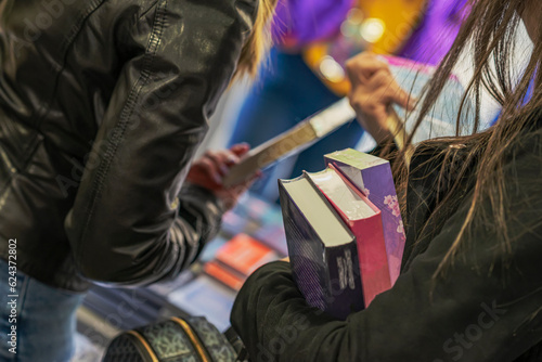 Close-up of girl hands with books, bookstore. Education, school, study, reading fiction concept. Real scene in store