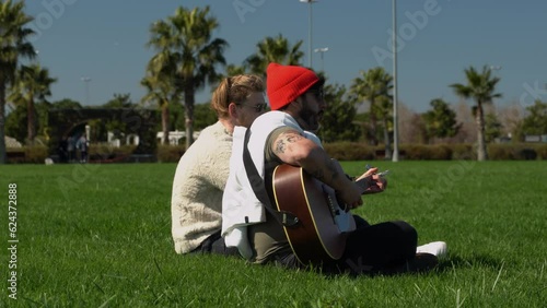 Two aspiring musicians rehearse outdoor performances. Lifestyle in green park, playing guitar in free time