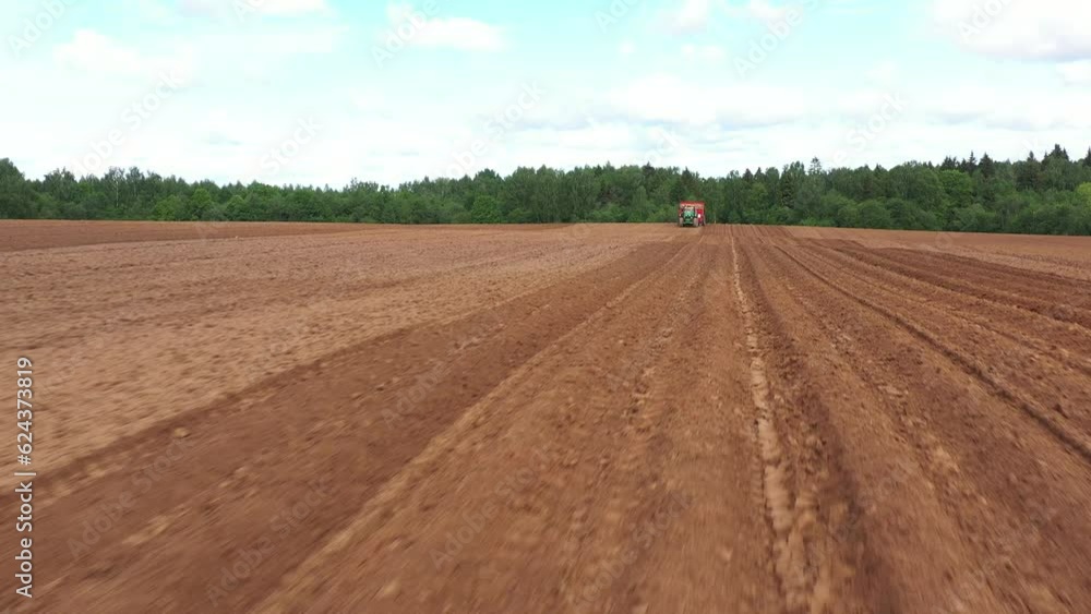 tractor plants potatoes in plowed potato field in spring, panoramic drone view tractor plants potatoes in plowed potato field in spring, panoramic drone view
