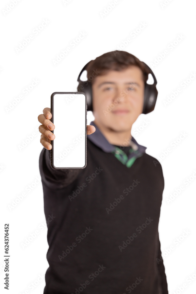 Caucasian boy with headphones out of focus shows the blank screen of his mobile phone isolated on a white background. Caucasian boy with headphones out of focus shows the blank screen of his mobile phone isolated on a white background.
