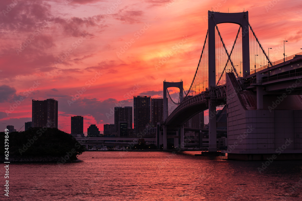 Beautifu firey sunset sky behing a suspension bridge and skyscrapers (Tokyo, Japan)