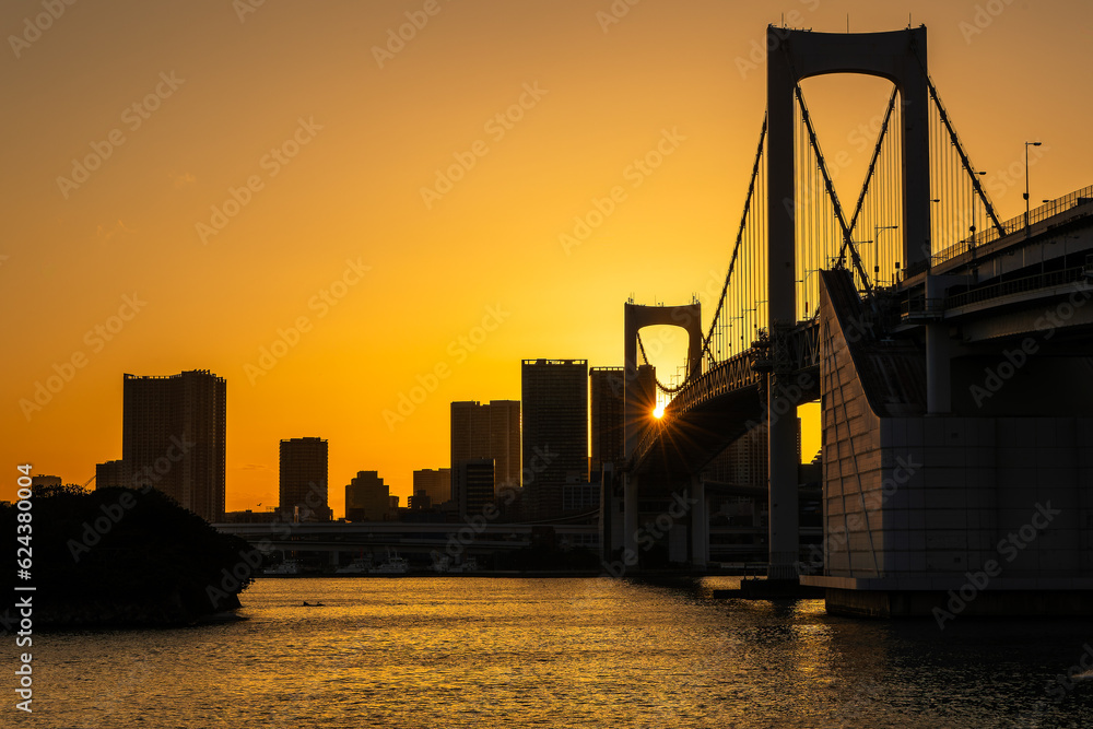 Orange sky as the sun sets behind the Rainbow Bridge and the Japanese capital city, Tokyo