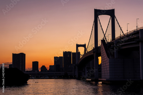 Purple and orange sky during sunset behind the skyscrapers of Tokyo and the Rainbow Bridge in Tokyo Bay