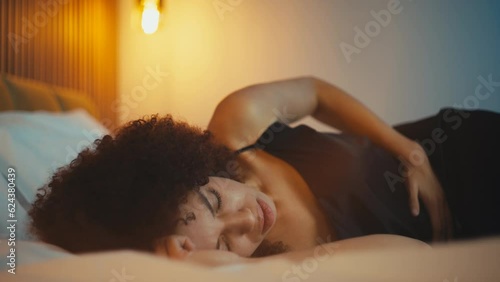 Unhappy young woman feeling strong stomach ache while lying on bed, gastritis photo
