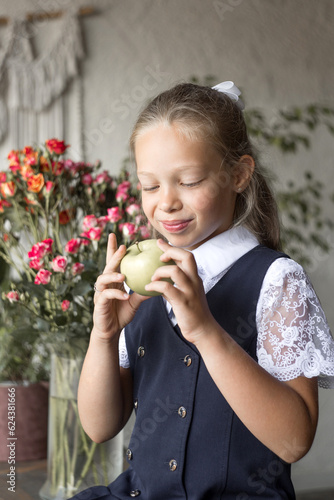 Primary schoolgirl, in school uniform, with apple.